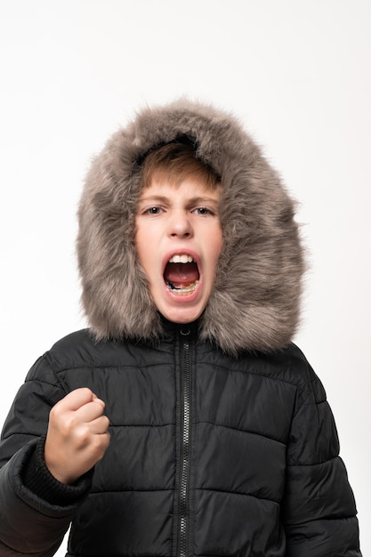 Um menino em uma jaqueta de inverno com capuz em um fundo branco