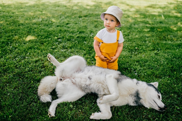 Um menino engraçado posando com o cachorro no jardim