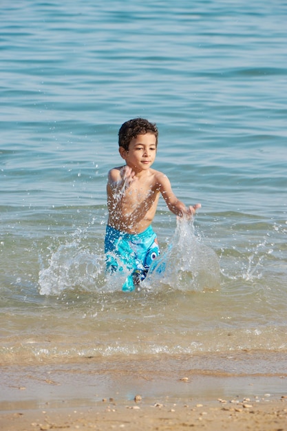 Um menino espirra na água na praia