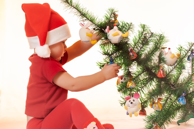 Um menino está procurando presentes do papai noel debaixo da árvore de natal.