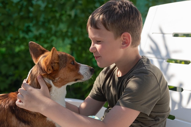 Um menino está segurando um cachorro de raça pura em seus braços Welsh corgi Pembroke Emoções positivas