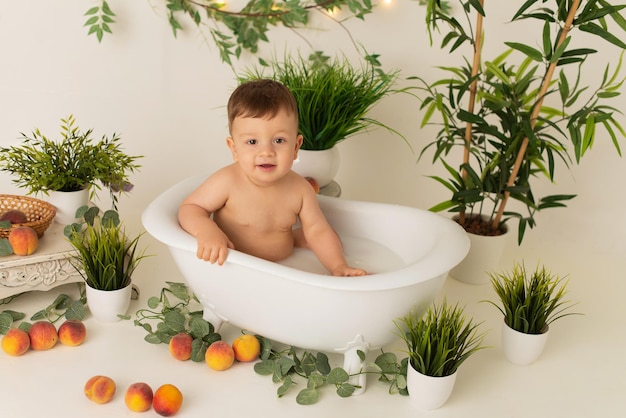 Um menino está sentado no banheiro com leite em um fundo branco com pêssegos e se alegra.