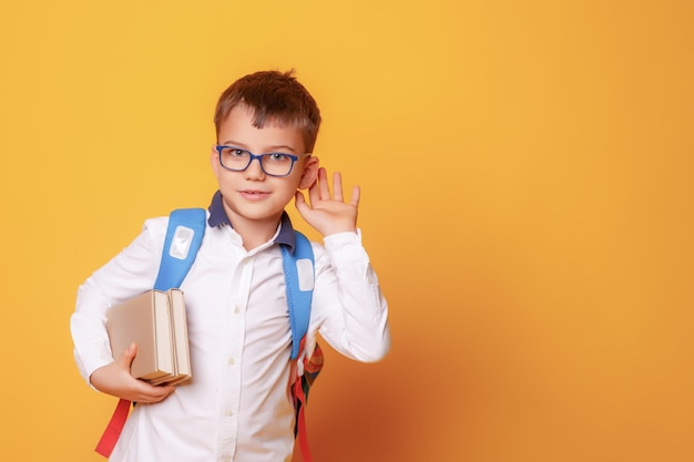 Um menino estudante segura livros e uma maçã em um fundo amarelo