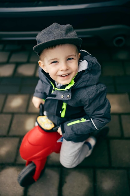Um menino feliz andando em seu veículo na rua e sorrindo para a câmera