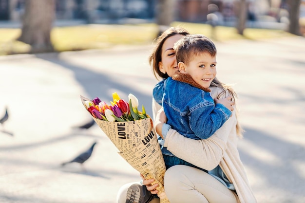 Um menino feliz surpreendeu sua mãe com flores no dia das mães