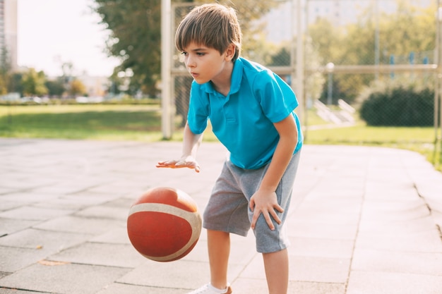 Um menino joga basquete depois da escola. Esportes, estilo de vida saudável, lazer