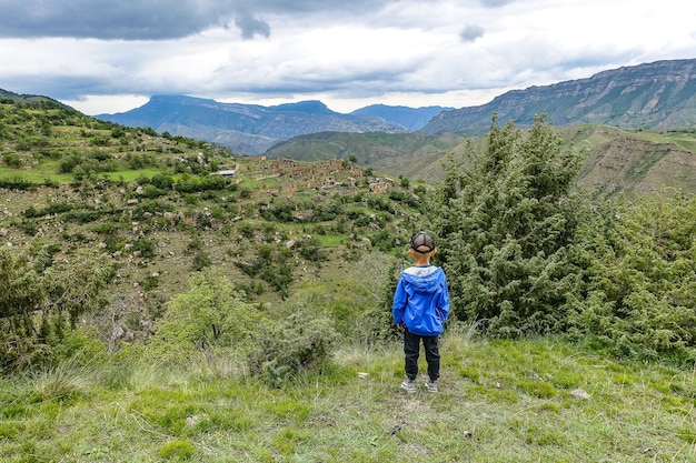 Um menino no fundo da aldeia de Kurib nas montanhas do Cáucaso no topo de um penhasco Daguestão Rússia junho de 2021