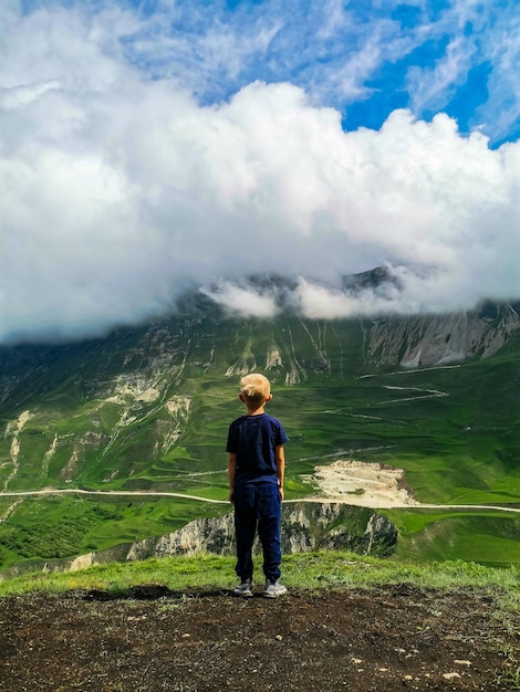 Um menino no fundo de belas montanhas verdes no Daguestão com nuvens Rússia