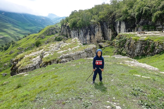 Um menino no fundo de uma paisagem montanhosa nas nuvens tigela de pedra no daguestão, rússia