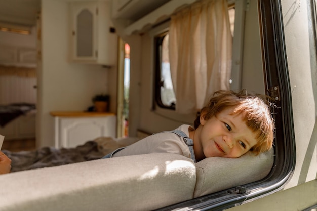 um menino pré-escolar aproveita o verão ao lado da autocaravana