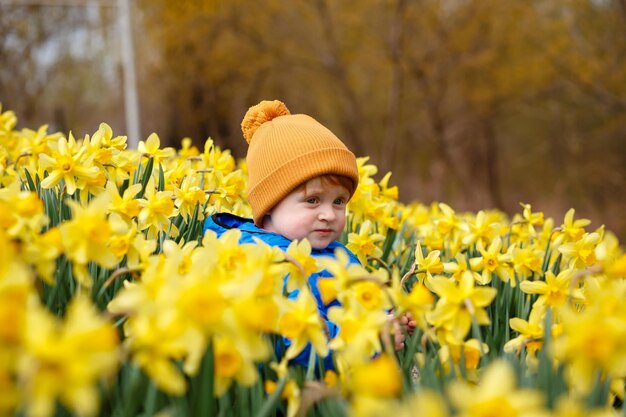 Foto um menino ruivo descansa no jardim de sua avó na aldeia entre narcisos