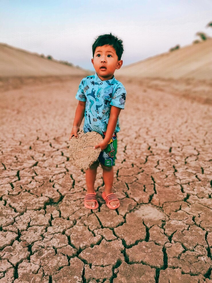 Foto um menino segurando o solo seco que ocorre de acordo com a estação