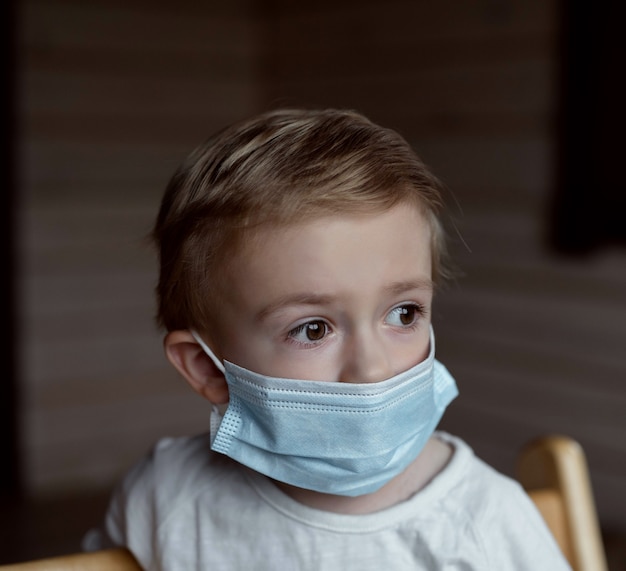 um menino sentado em uma máscara médica