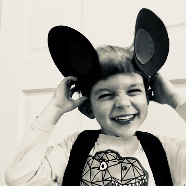 Foto um menino sorridente disfarçado a fazer uma cara em casa.
