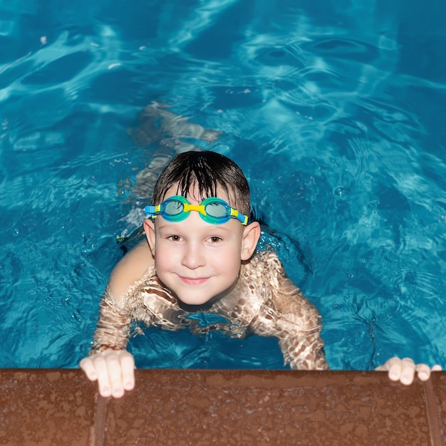 Um menino sorridente está nadando na piscina Esportes e recreação Pessoas bonitas