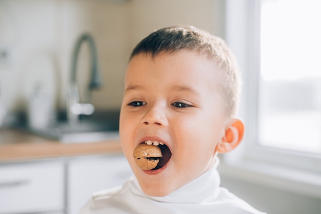 Um menino tenta quebrar uma noz mostrando dentes de leite fortes e saudáveis, faz um esforço