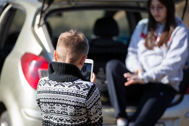 Um menino tira uma foto de uma menina em um smartphone