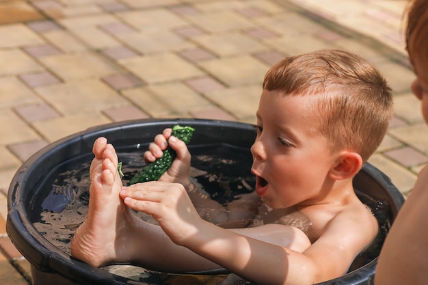 Um menino toca um inseto louva-a-deus em um dia de verão na vila conceito insetos de verão