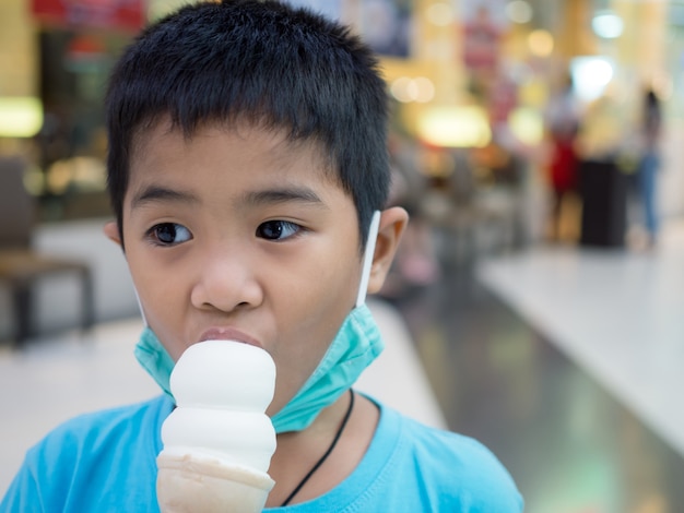 Um menino tomando sorvete dentro de um shopping