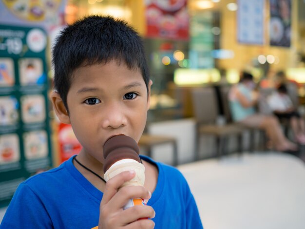 Um menino tomando sorvete dentro de um shopping