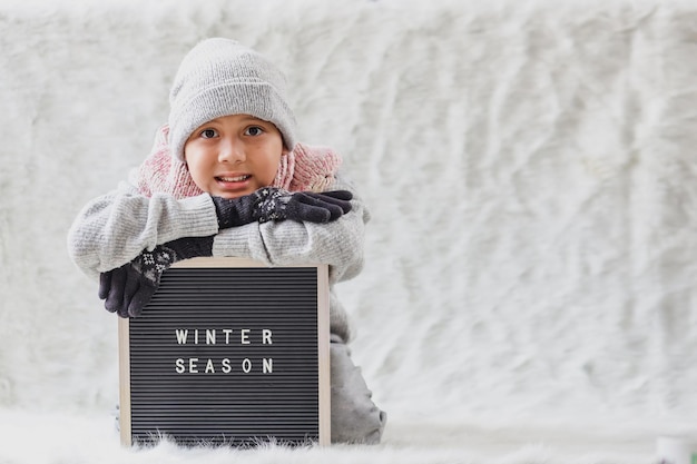 Um menino vestindo roupas de inverno dá as boas-vindas ao inverno com alegria