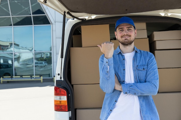 Um mensageiro com um tablet nas mãos perto de um carro com caixas