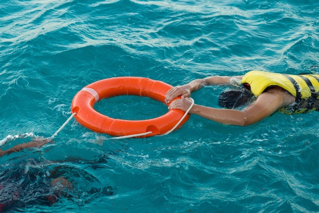 Um mergulhador barbudo em um colete salva-vidas segura uma bóia salva-vidas na água do mar azul transparente