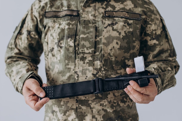 Um militar demonstra um torniquete médico de combate para parar o sangue durante os primeiros socorros Instruções para equipamentos táticos de combate