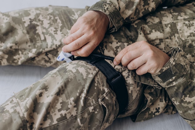 Um militar demonstra um torniquete médico de combate para parar o sangue durante os primeiros socorros Instruções para equipamentos táticos de combate