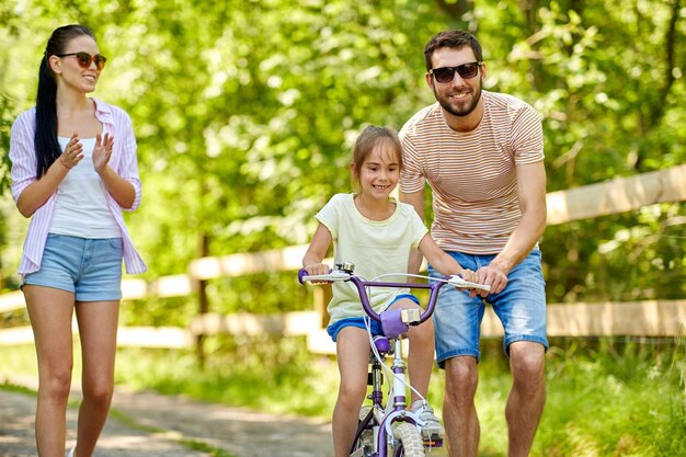 Um miúdo com patentes a aprender a andar de bicicleta no parque.