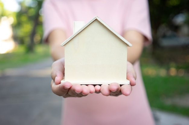 Um modelo de casa modelo é colocado nas mãos da menina asiática do negócio.