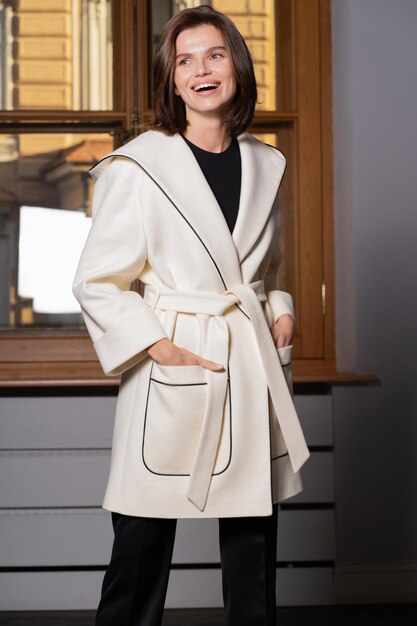 Um modelo feminino posando mostra um elegante casaco bege Uma loja de roupas femininas da moda