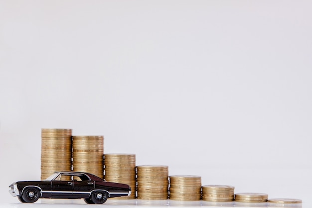 Um modelo preto de um carro com moedas na forma de um histograma sobre um fundo branco. conceito de empréstimo, poupança, seguro.