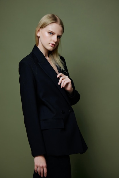 Um modelo profissional atraente e legal segura uma jaqueta pelo colarinho da lapela e posa sobre um fundo verde-oliva no estúdio Banner legal para marcas