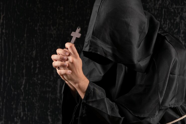 Foto um monge rezando com um rosário e um crucifixo na mão