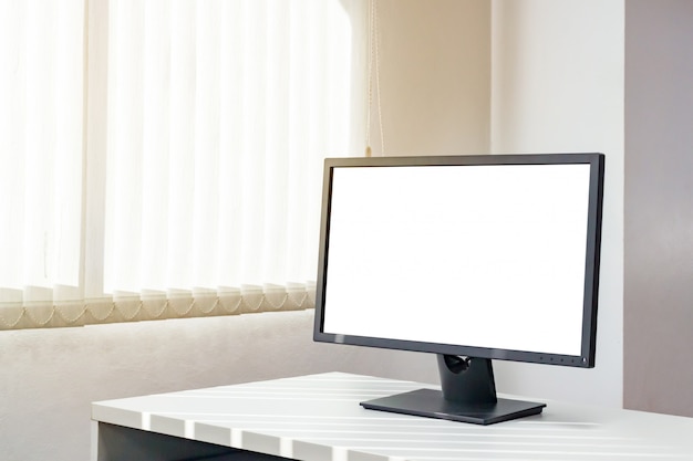 Um monitor da tela em branco no desktop com luz do sol da janela. Imagem com espaço da cópia.