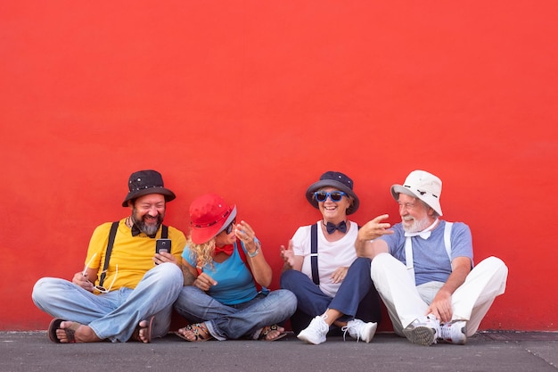 Foto um monte de amigos com chapéus sentados contra a parede.