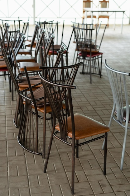 Um monte de cadeiras em cima umas das outras em uma pilha em um café fechado devido à quarentena. Foco seletivo
