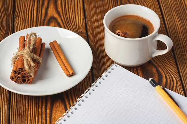 Um monte de canela de malha com uma corda, uma xícara de café e um caderno para escrever