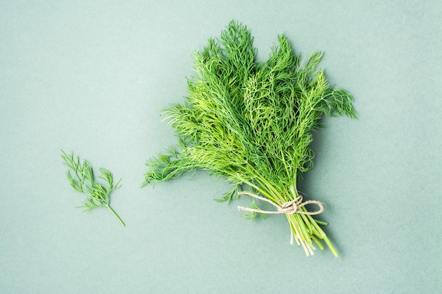 Um monte de endro fresco amarrado com uma corda em um fundo verde. Vitaminas verdes em uma dieta saudável. Vista do topo