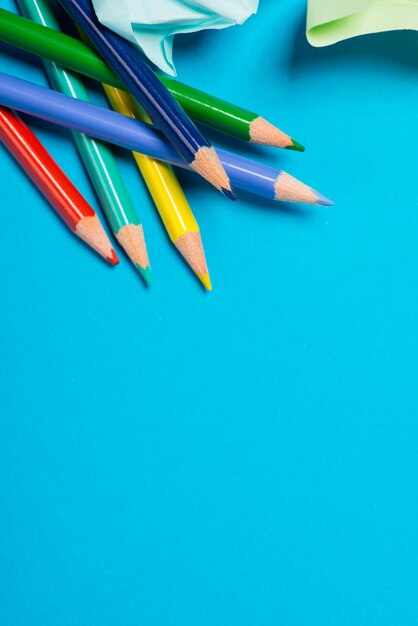 Um monte de lápis de cor em uma superfície azul