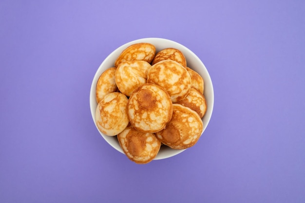 Foto um monte de mini panquecas de cereais em uma tigela em um fundo brilhante