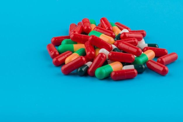 Um monte de pílulas coloridas misturadas em um fundo azul