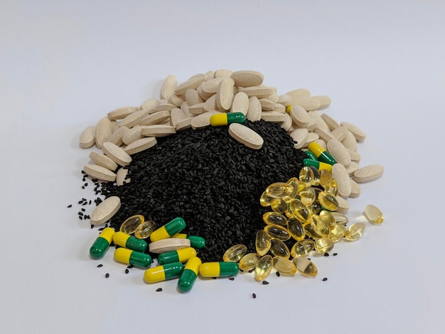 Um monte de pílulas e sementes pretas em fundo isolado
