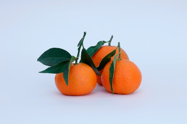 Um monte de tangerinas com folhas verdes sobre um fundo branco.