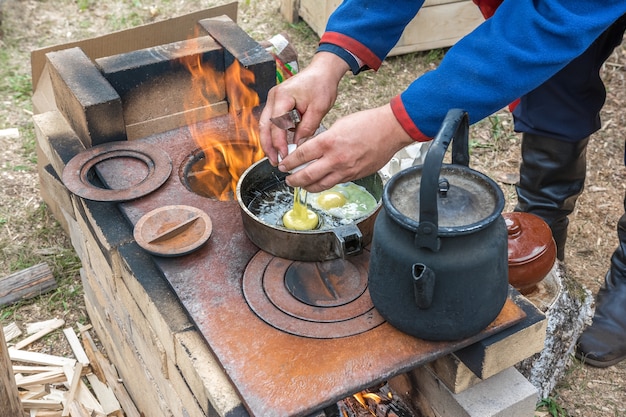 Um morador está fritando ovos fritos em uma fogueira do lado de fora de casa Comida e estilo de vida rústicos