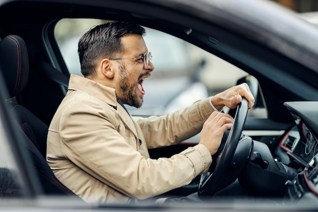 Um motorista da moda irritado está buzinando em outros motoristas enquanto está sentado em um carro