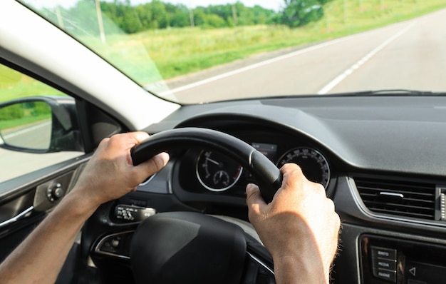 Um motorista do sexo masculino dirige um carro na estrada com as mãos no volante conceito tavel viajando diariamente