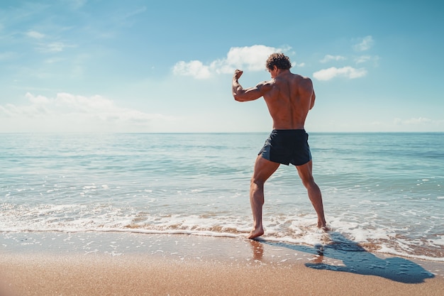 Um muay thai ou kickboxer treinando com boxe de sombra ao ar livre na praia