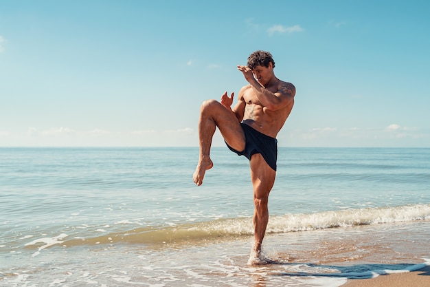 Um muay thai ou kickboxer treinando com boxe de sombra ao ar livre na praia